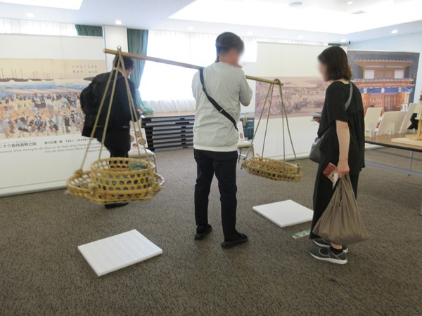 男性が「棒手振り」を肩に乗せている写真