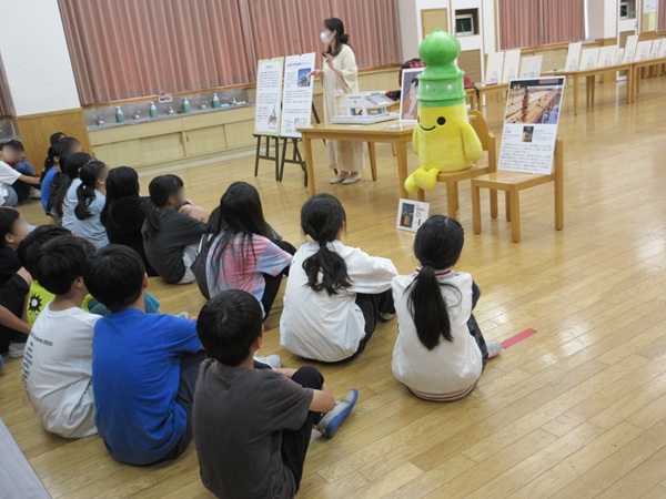 児童が座って学芸員の説明を聞いている写真